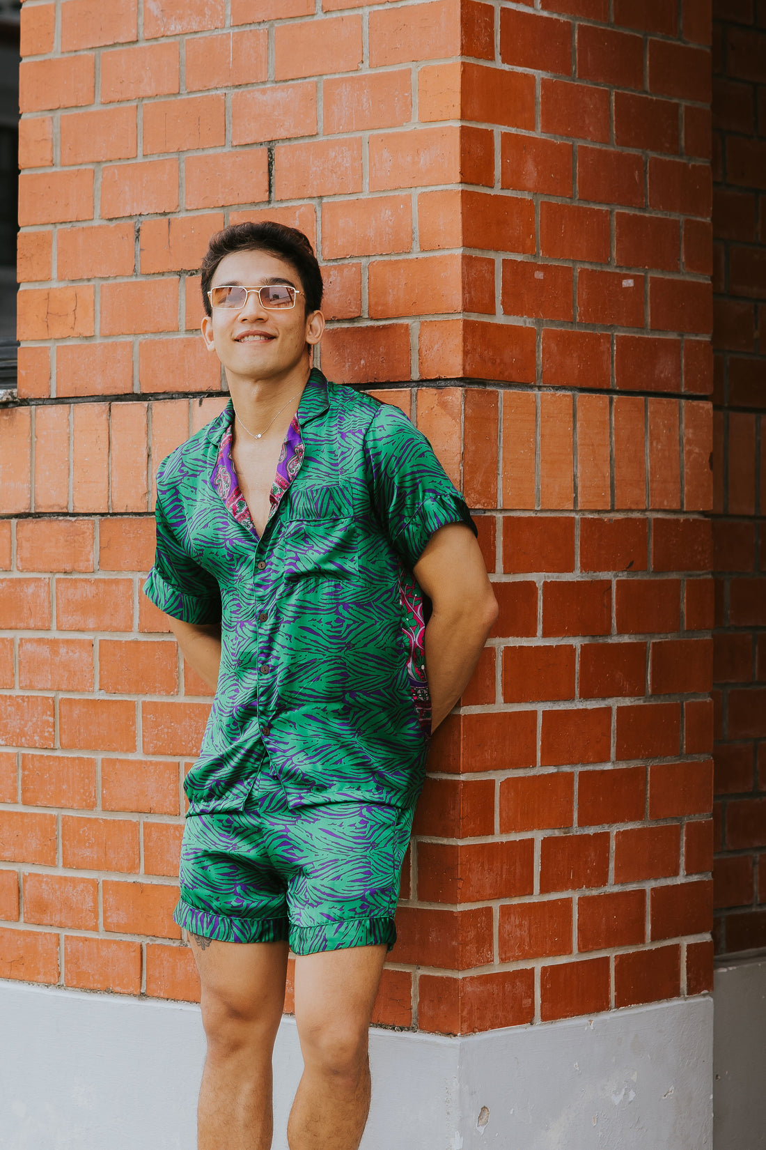 Model wearing Raja Rani Purple Green Jungle Holiday Set in a vibrant green and purple jungle print with matching shirt and shorts.