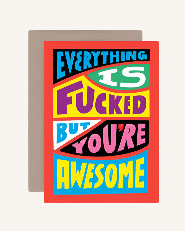 A colorful greeting card with the text 'EVERYTHING IS F***ED BUT YOU'RE AWESOME' on a red background, with a brown envelope.
