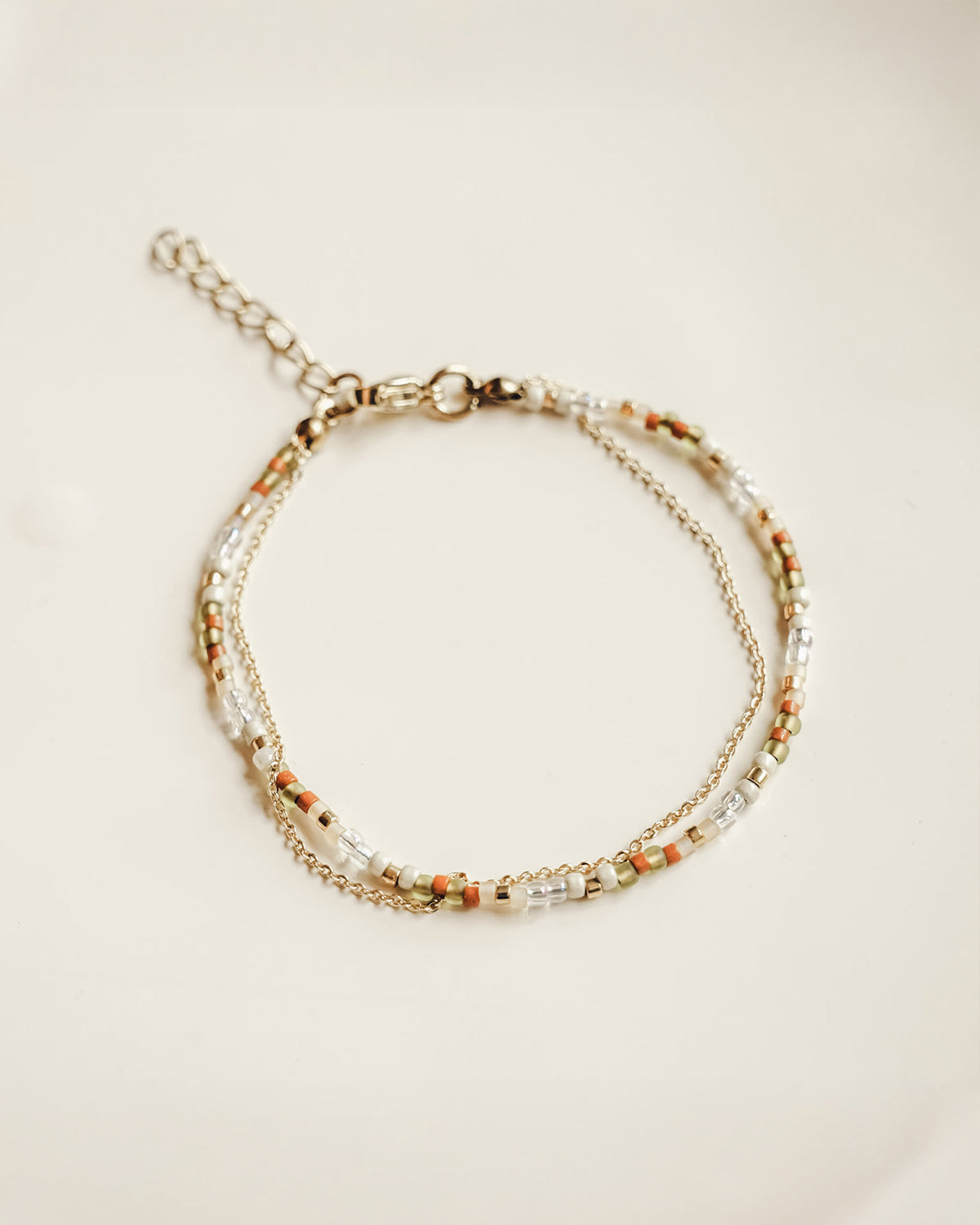 handmade earth toned beaded bracelet layered with dainty gold-plated chain