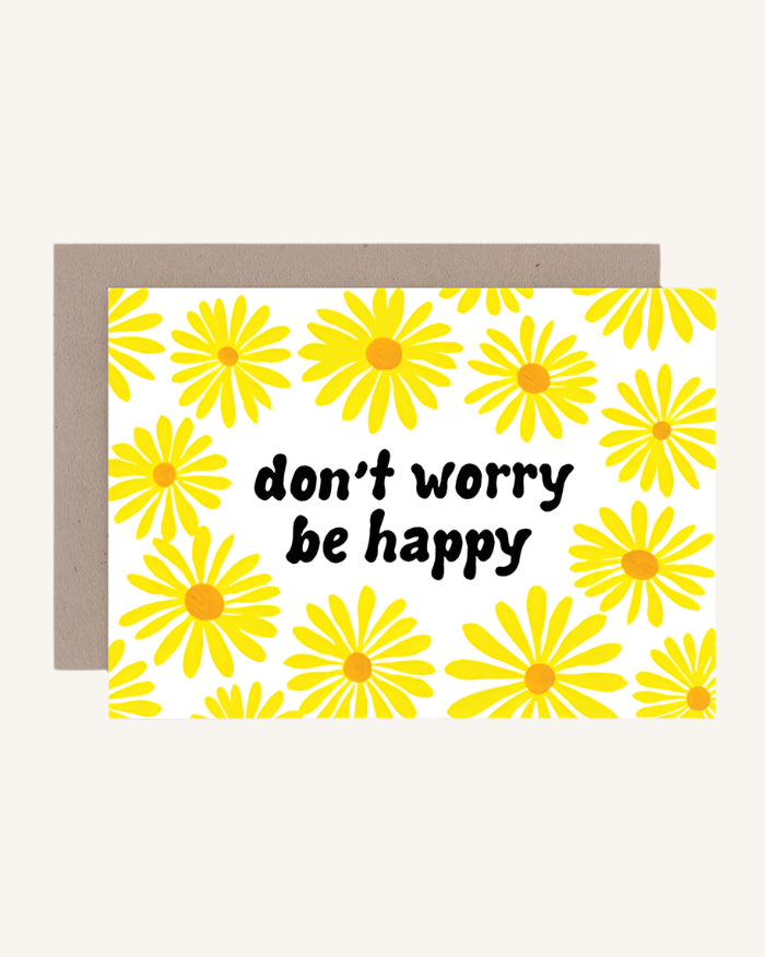 A greeting card with yellow flowers and the text 'don't worry be happy' on it, accompanied by a brown envelope.