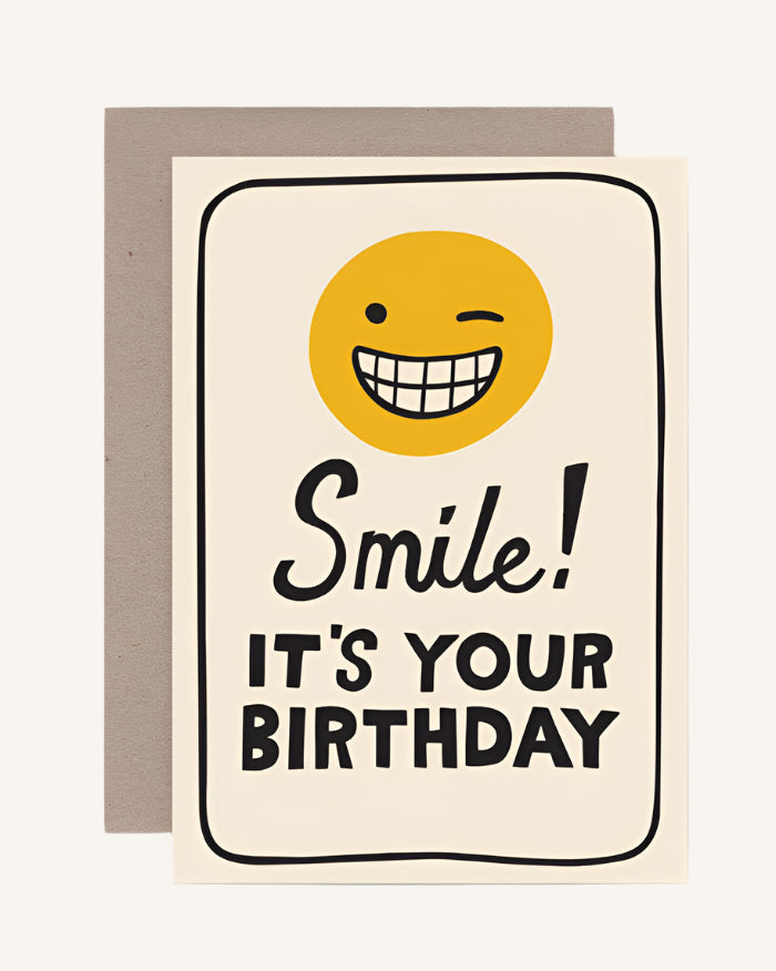 A greeting card with a smiling sun character and the text 'Smile! It's Your Birthday' on it, accompanied by a brown envelope.