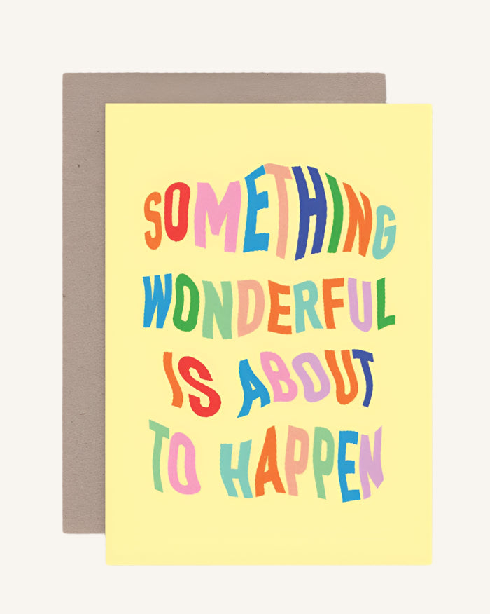 Greeting card with colorful text 'Something wonderful is about to happen' on a yellow background