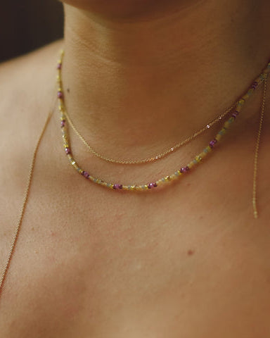 Model wearing Envet Berry Twist Necklace, a layered beaded and gold chain necklace styled on the neckline