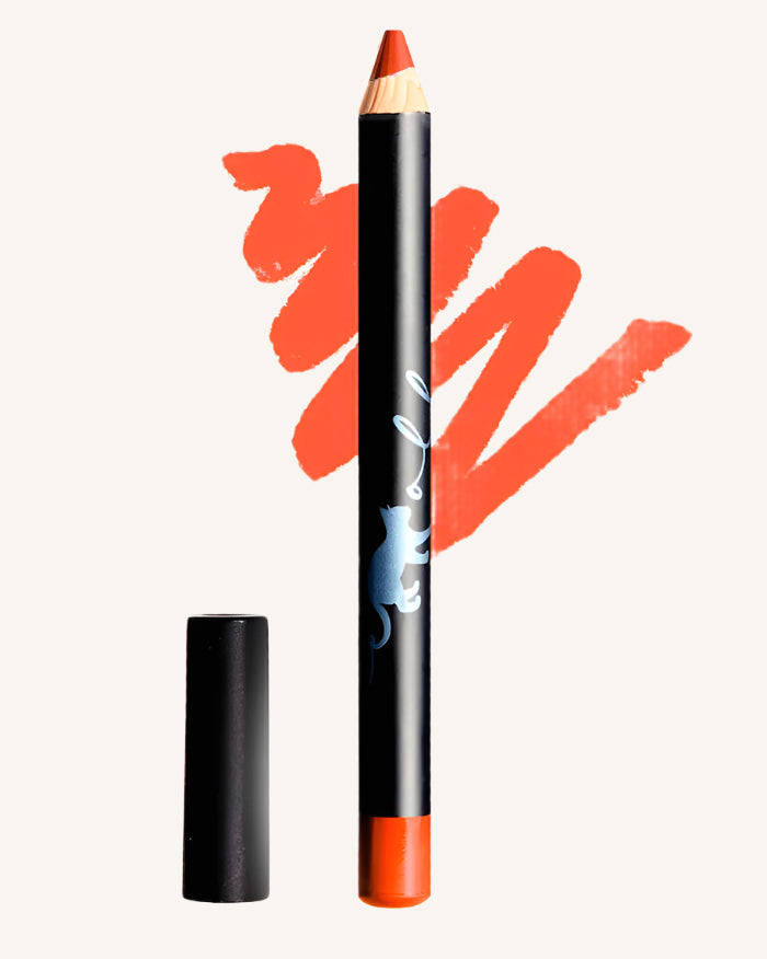 A close-up of a Bluemolly lip crayon in the shade Coral, showing the product with its cap removed, alongside a swatch of the coral color lipstick.