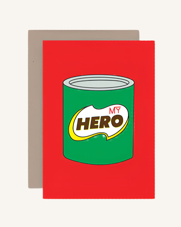 A red greeting card with a graphic of a green and yellow can labeled 'MY HERO' on the front, and a brown envelope included.