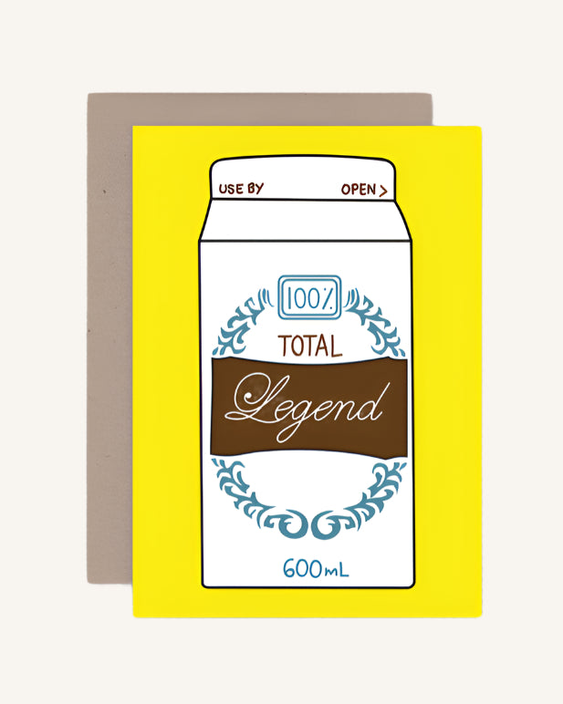 A yellow greeting card with a cartoon illustration of a milk carton labeled '100% Total Legend' in various colors, including brown and blue.